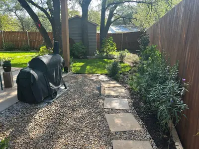 After: stepping stones along a planted fence line beside the patio and green lawn.