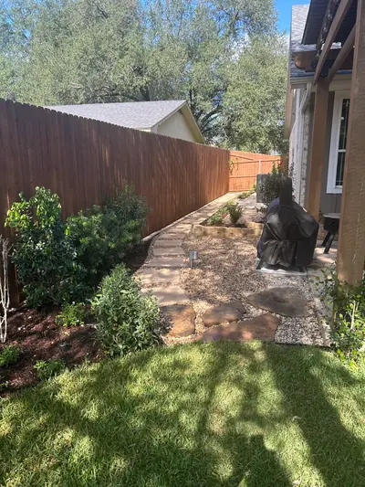 After: a gravel and stone walkway leading from the lawn past planted beds beside the house.