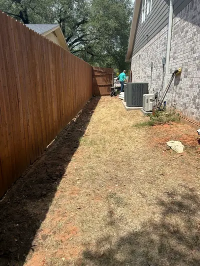 Before: dry grass between the house and wooden fence before the stone walkway and planted border.