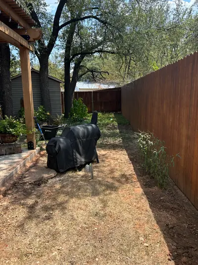 Before: a dry grassy area beside the covered patio, grill, and wooden fence.